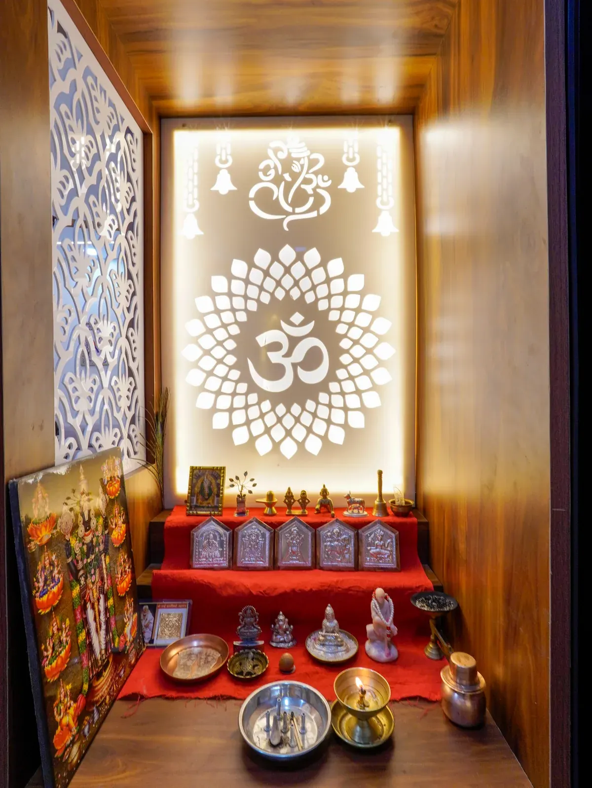 An illuminated prayer space with an Om motif, decorative patterned panel and timber finishes.